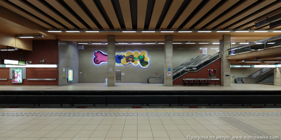 Станция Joséphine-Charlotte [Жозефи́н-Шарло́тт] (линия 1, Брюссель). Стены над обоими спусками на станцию украшены барельефами «Уникальный цветок или прекрасные птицы».