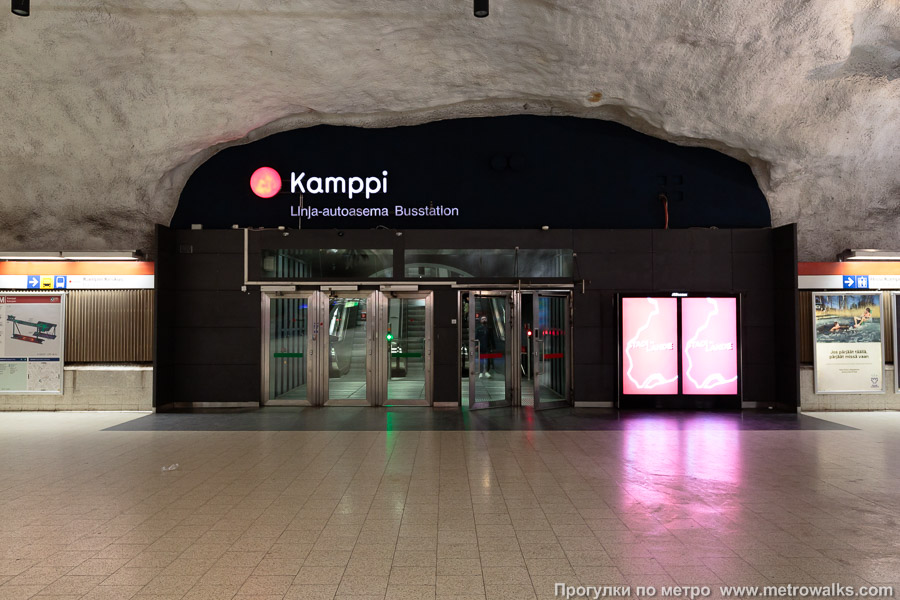 Станция Kamppi / Kampen [Ка́мппи] (Хельсинки). Выход в город, эскалаторы начинаются прямо с уровня платформы. Восточный выход — в торговый комплекс «Kamppi» и на подземный автовокзал.