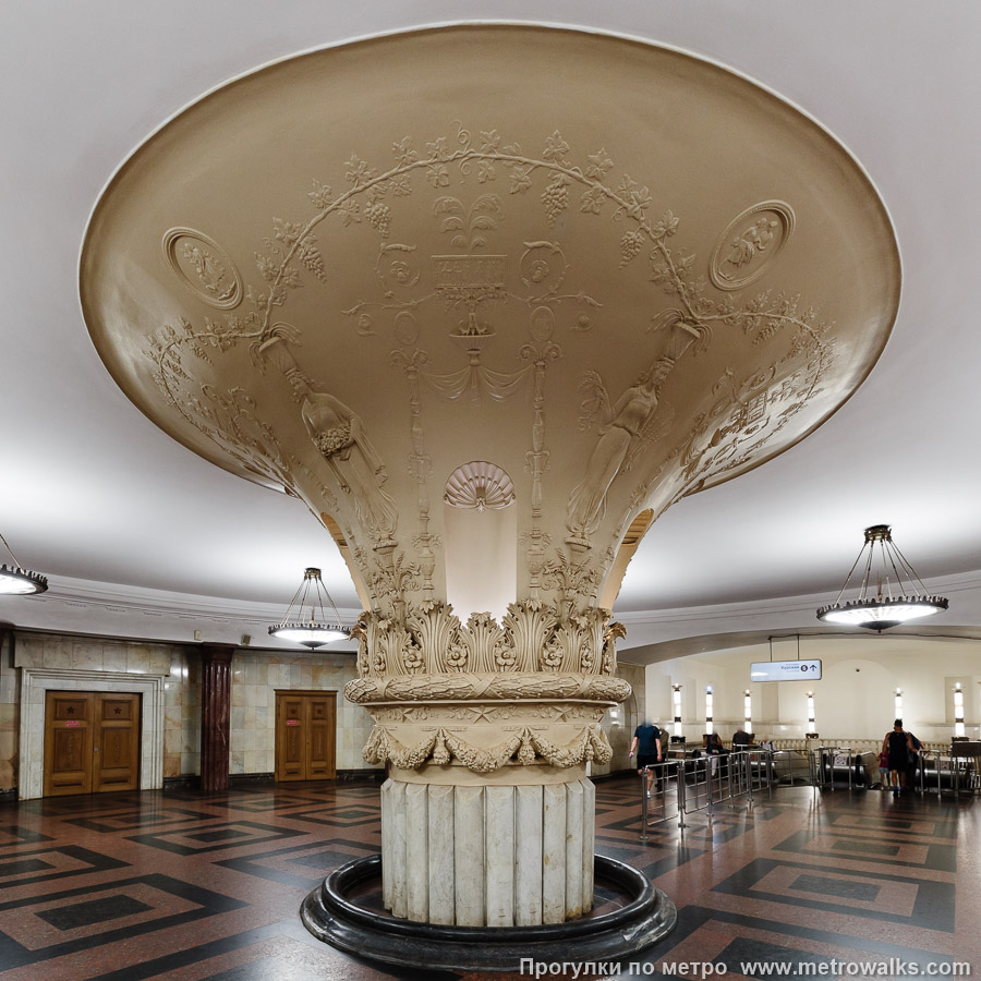 Станция Курская (Кольцевая линия, Москва). Центр эскалаторного зала занимает столп, расширяющийся кверху и украшенный лепниной с разнообразными растениями и барельефами сельскохозяйственной тематики.