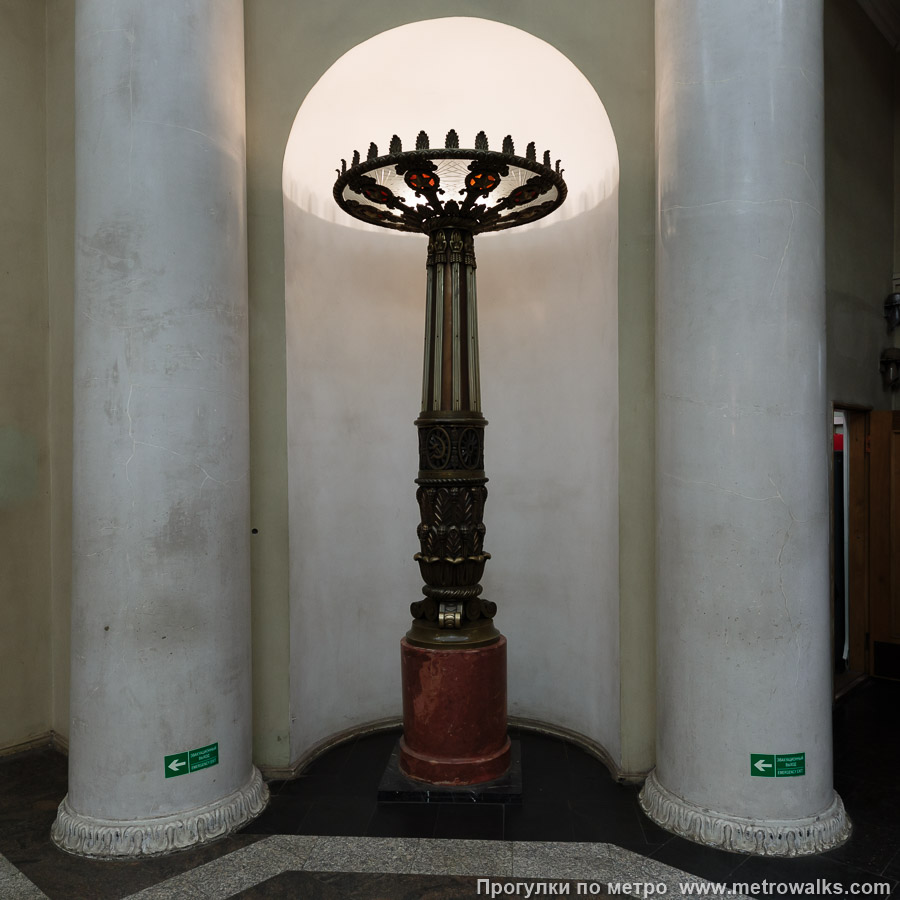 Станция Кировский завод (Кировско-Выборгская линия, Санкт-Петербург). Эскалаторный зал, помимо закарнизного света, освещён четырьмя высокими напольными торшерами на мраморных основаниях.