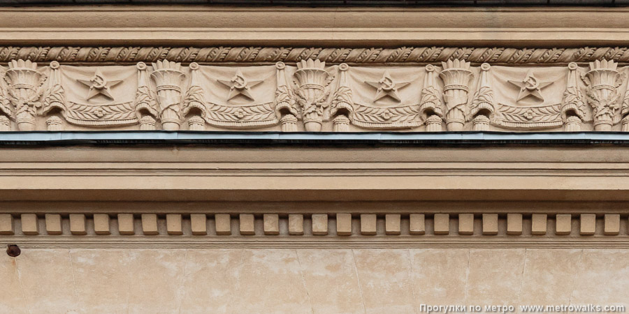 Станция Кировский завод (Кировско-Выборгская линия, Санкт-Петербург). Архитектурное оформление вестибюля. Прикарнизный фриз с типовыми символами эпохи СССР — звёздами, серпами-и-молотами, знамёнами, факелами, дубовыми ветвями.