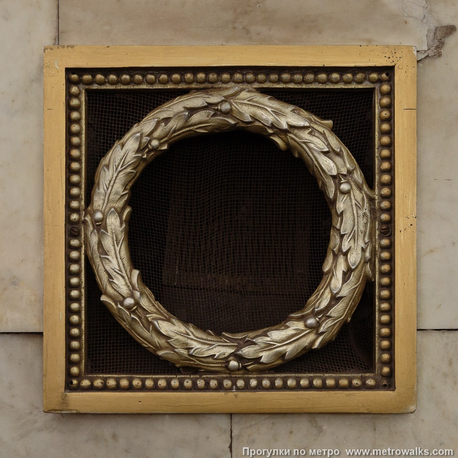 Станция Владимирская (Кировско-Выборгская линия, Санкт-Петербург). Декоративная отделка стены в проходе к эскалаторам. Декоративная решётка в виде дубового венка, скрывающая вентиляцию или громкоговоритель. Это типовой элемент станций первой очереди.