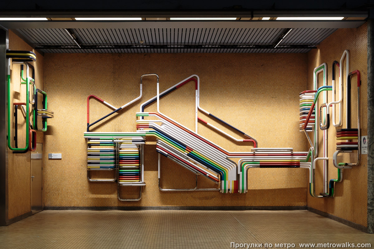 Фотография станции Botanique / Kruidtuin [Ботани́к / Кра́утаун] (линия 2 / 6, Брюссель). Декоративное оформление станционной стены крупным планом. Окрашенные и эмалированные стальные трубы ярких цветов символизируют трамвайные линии, напоминая, что станции метро Брюсселя сначала были станциями подземного трамвая.