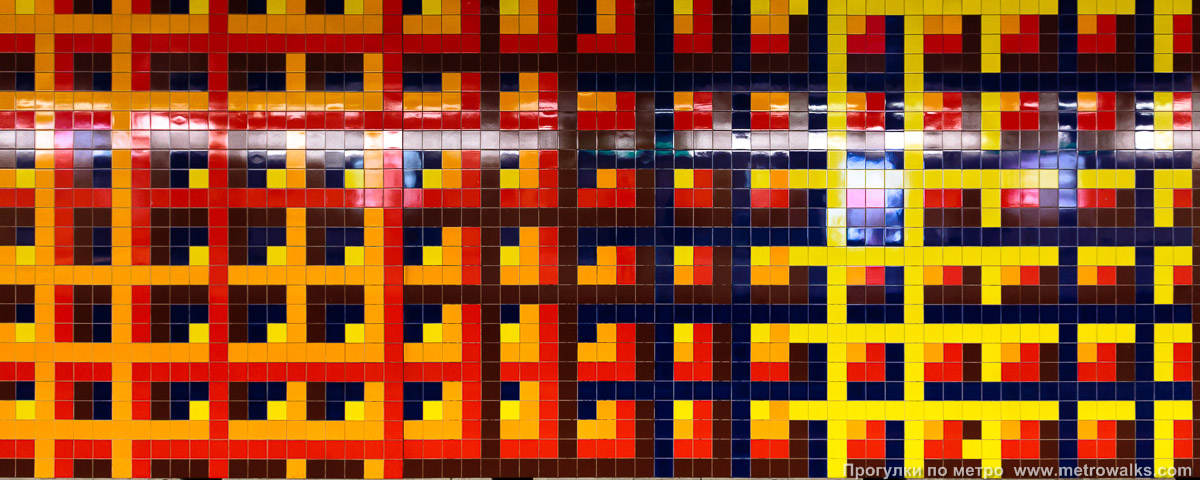Фотография станции Merode [Меро́д] (линия 1, Брюссель) — второй зал. Декоративное оформление путевой стены крупным планом. Путевая стена в зале второго пути украшена разноцветной керамической плиткой с регулярным чередованием цветов от жёлтого и красного до синего и коричневого, от которого рябит в глазах.