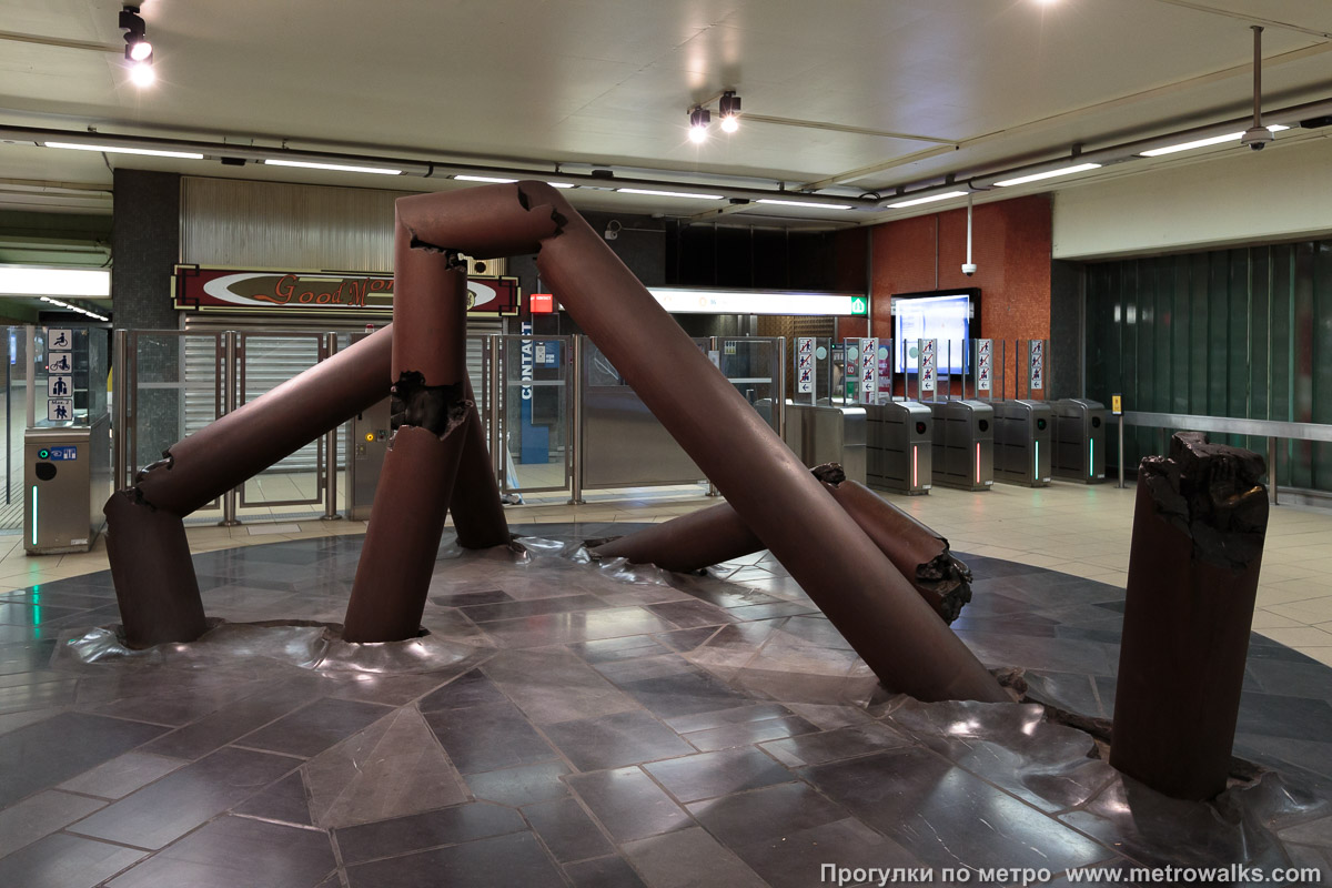 Фотография станции Thieffry [Тьиффри́] (линия 5, Брюссель). Скульптура в вестибюле. В вестибюле — скульптура из металлических столбов; в местах надломов можно разглядеть фрагменты человеческих тел. Скульптор — Феликс Рулан (Félix Roulin).