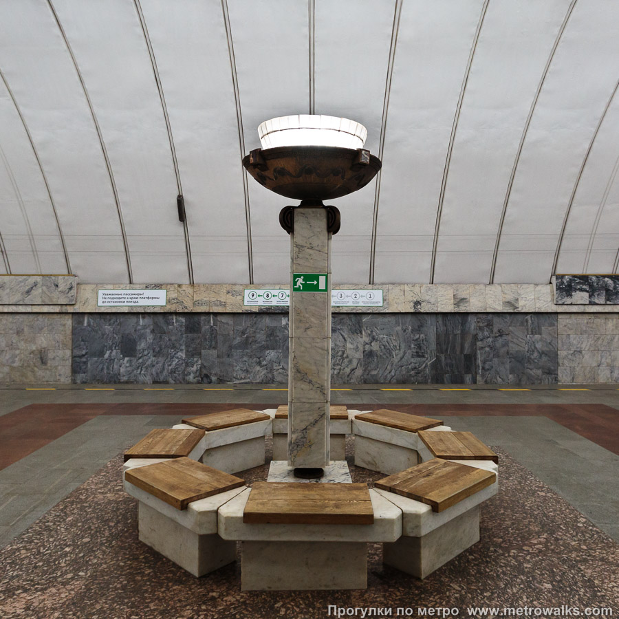Фотография станции Динамо (Екатеринбург). Скамейка. По оси станции внутри колец из скамеек установлено пять светильников, изображающих факелы.