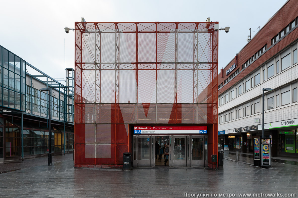 Фотография станции Itäkeskus / Östra centrum [И́тяке́скус] (Хельсинки). Вход в наземный вестибюль крупным планом. Вход на платформу в сторону центра — отдельный павильон во дворе торгового комплекса.