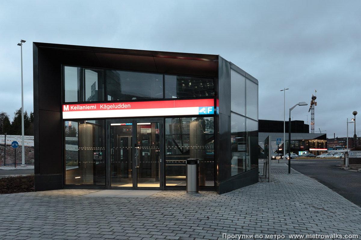 Фотография станции Keilaniemi / Kägeludden [Ке́йланиэ́ми] (Хельсинки). На станцию можно спуститься на лифте прямо с улицы. Лифт ведёт в подземный этаж вестибюля, где можно пройти к другому лифту, ведущему на платформу.