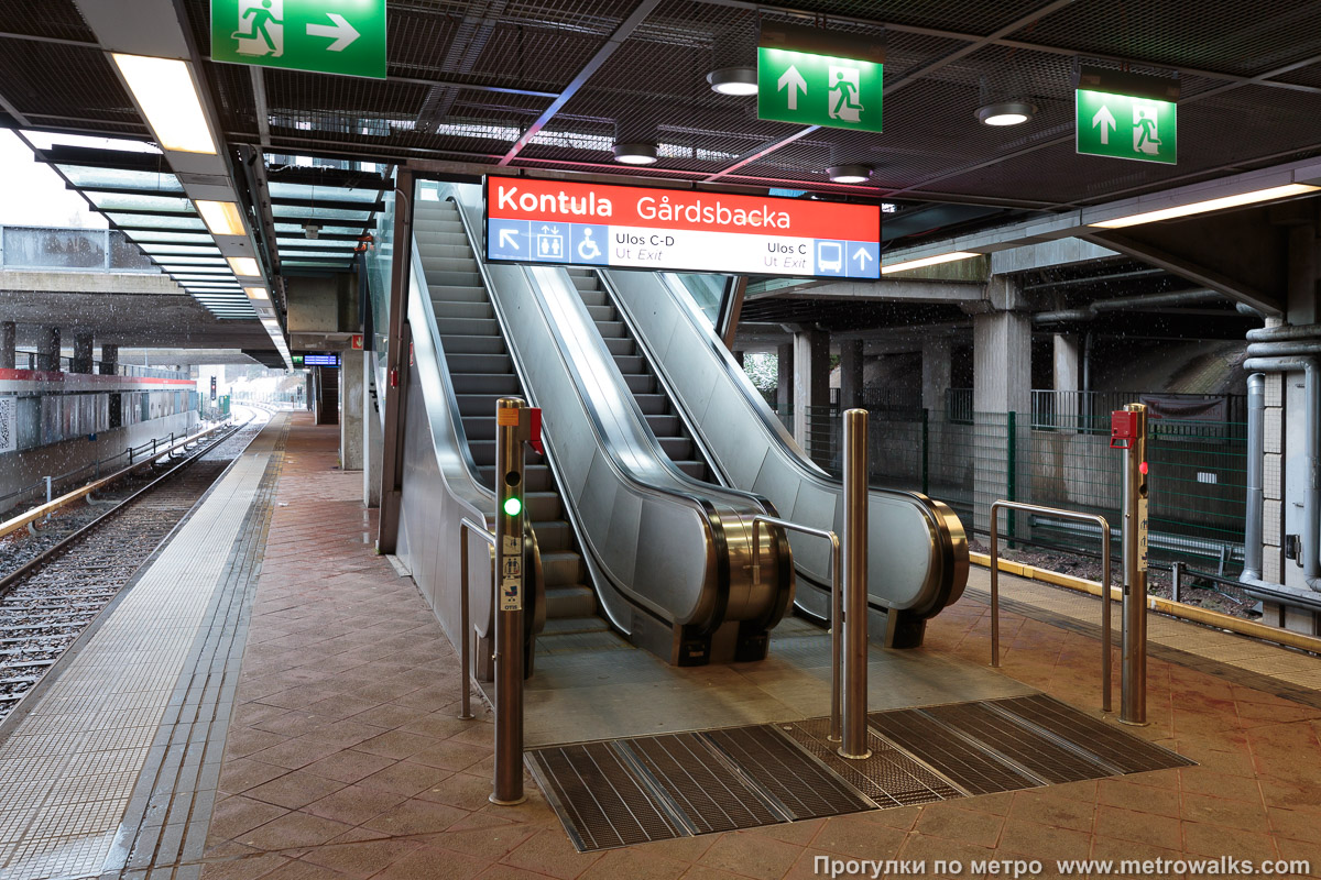 Фотография станции Kontula / Gårdsbacka [Ко́нтула] (Хельсинки). Выход в город, эскалаторы начинаются прямо с уровня платформы. Второй выход — в центральной части платформы.