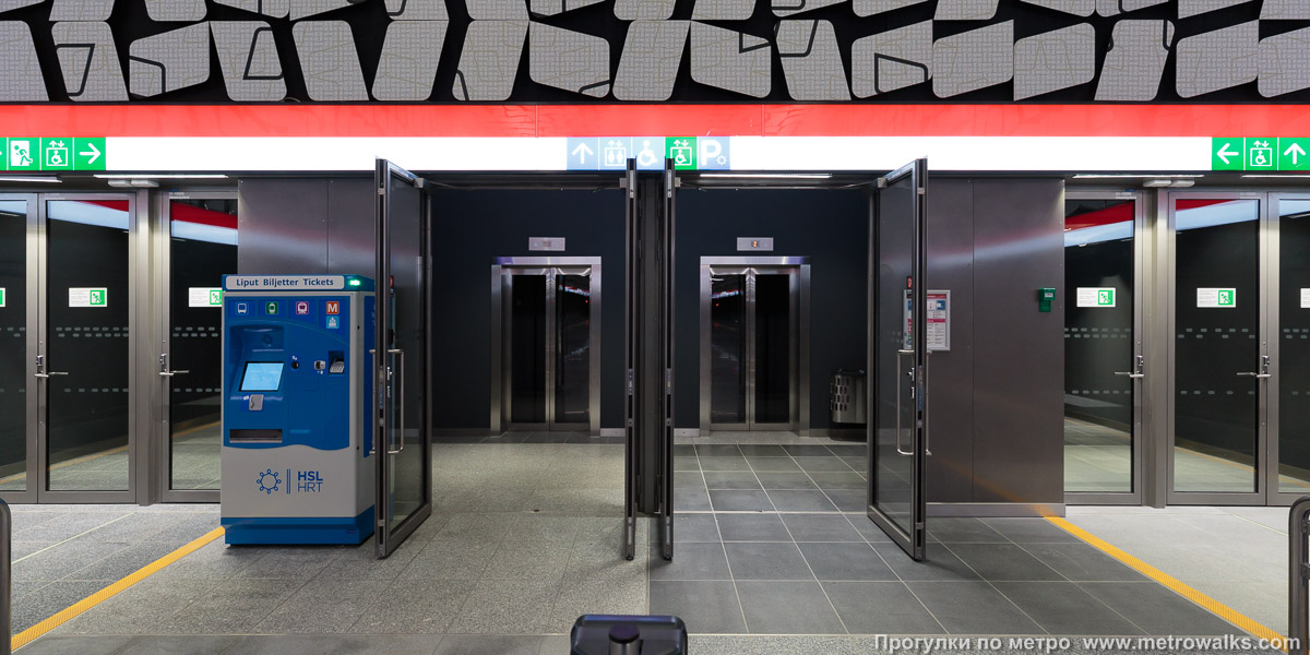 Фотография станции Urheilupuisto / Idrottsparken [У́рхейлупу́йсто] (Хельсинки). Лифт. Лифты с противоположной от эскалаторов части станции.