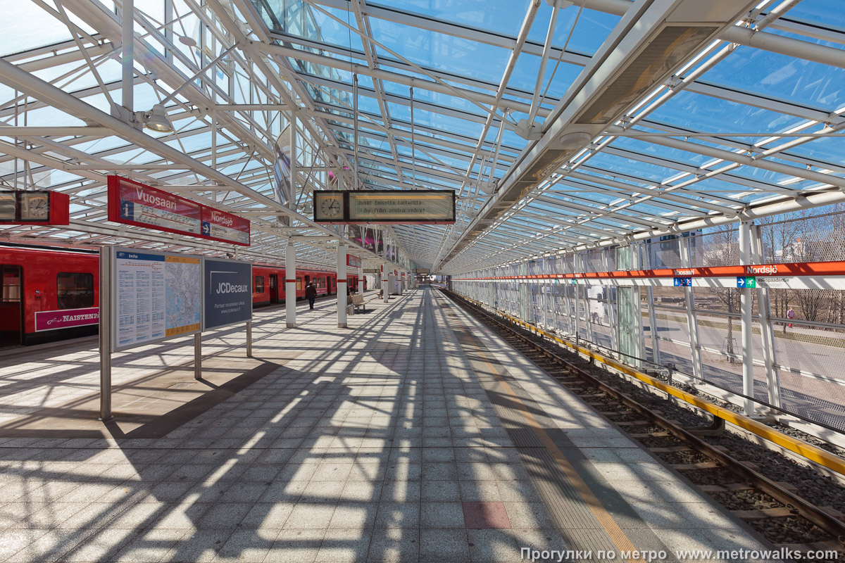 Фотография станции Vuosaari / Nordsjö [Вуо́саа́ри] (Хельсинки). Продольный вид вдоль края платформы. Историческое фото 2009 года с жидкокристаллическим табло, которые уже давно не используются.