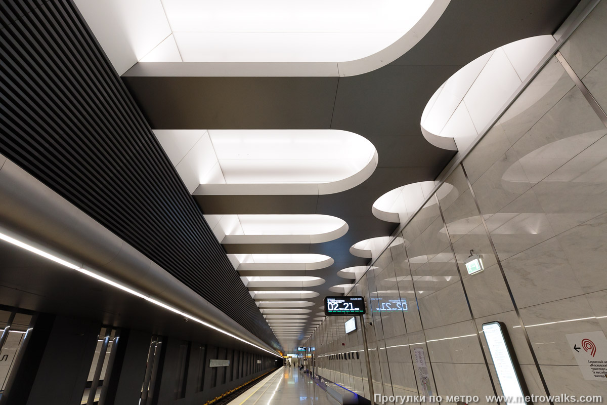 Фотография станции Текстильщики (Большая кольцевая линия, Москва). Взгляд наверх. Основной элемент декора станции — световые ниши в потолке устроены согласованно с элегантными вертикальными металлическими накладными полосами на стенах.