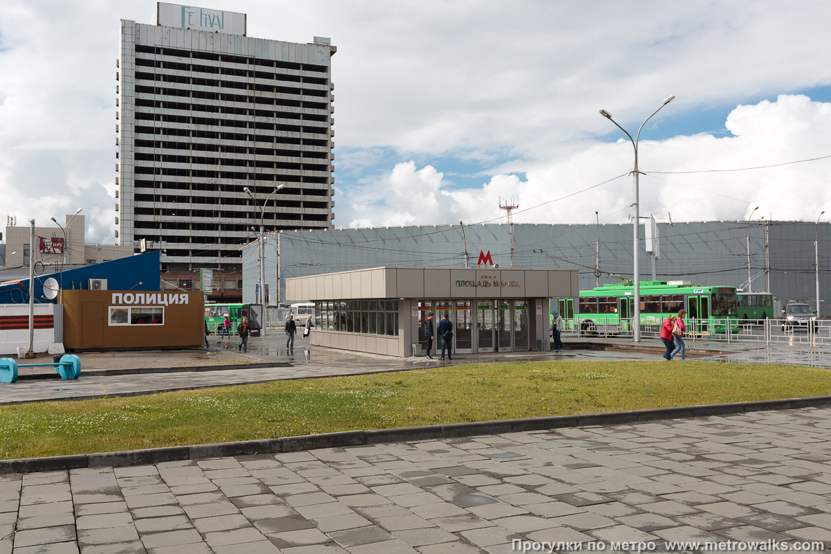 Фотография станции Площадь Маркса (Ленинская линия, Новосибирск). Вход на станцию осуществляется через подземный переход. Некоторые из входов в подземный переход встроены в торговые здания (на заднем плане).