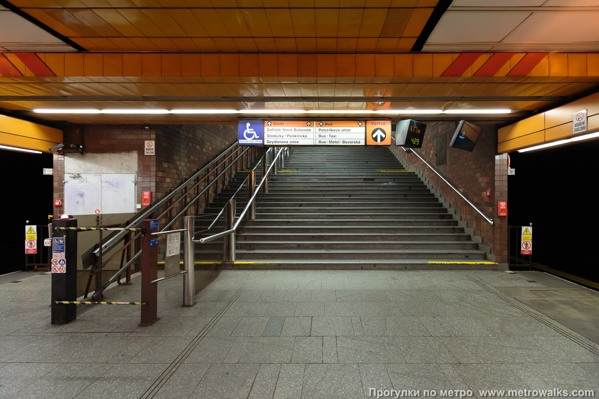 Фотография станции Nové Butovice [Но́ве Буто́вице] (линия B, Прага). Выход в город осуществляется по лестнице. Западный выход. Загородка слева — не ремонтные работы, а рельсовый подъёмник для инвалидных кресел.