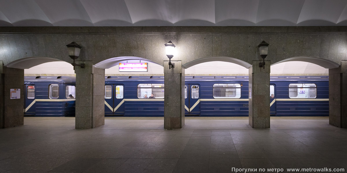 Фотография станции Достоевская (Правобережная линия, Санкт-Петербург). Поперечный вид, проходы между колоннами из центрального зала на платформу. Для пущей цветастости — с поездом.