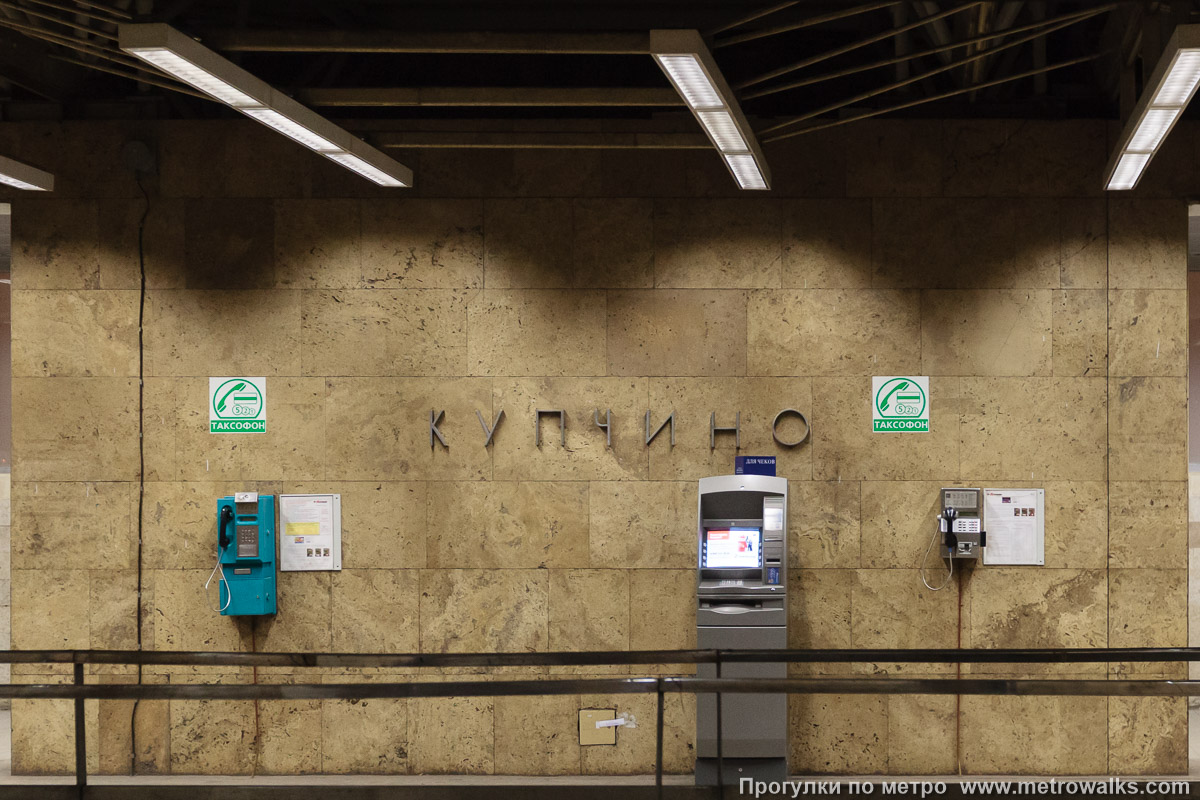 Фотография станции Купчино (Московско-Петроградская линия, Санкт-Петербург). Название станции на станционной стене крупным планом. Старинная фотография 2010 года, когда на многих станциях были проводные телефоны.