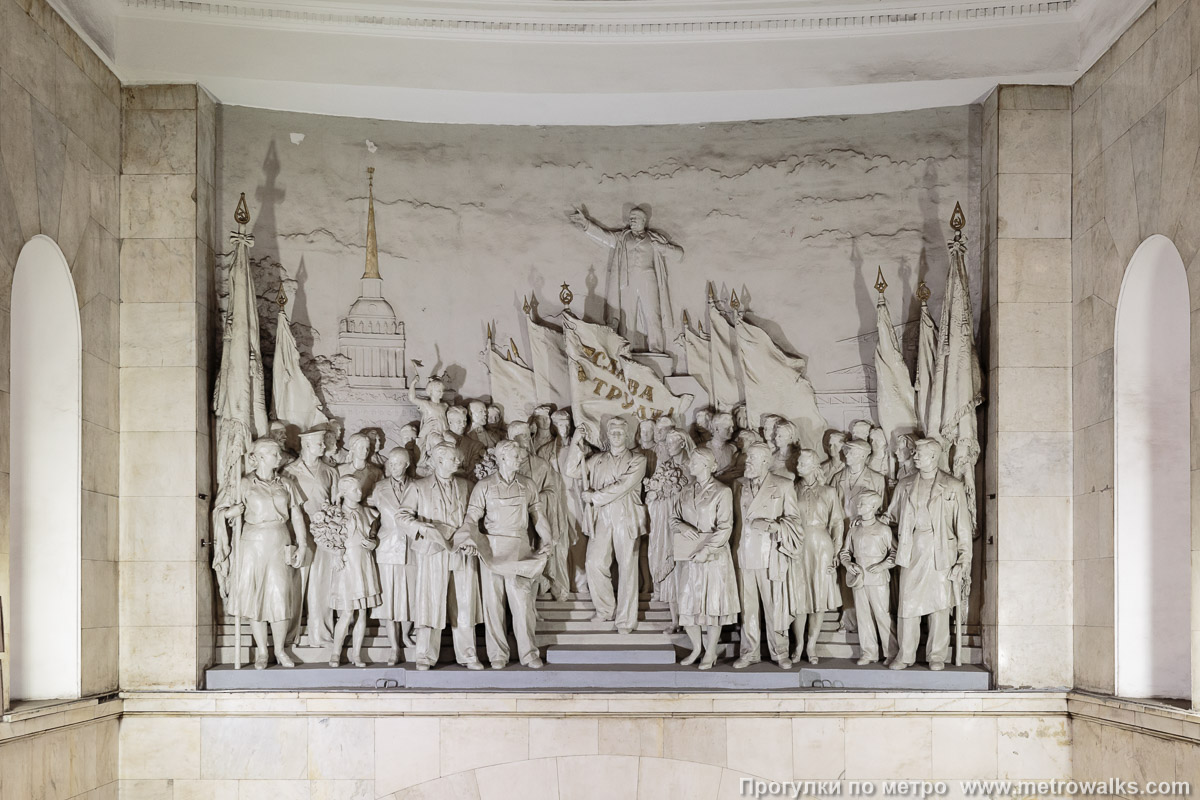 Фотография станции Нарвская (Кировско-Выборгская линия, Санкт-Петербург). Декоративное оформление стены над спуском. Горельеф «Слава Труду!», в центре которого планировалась скульптура Сталина. Скульпторы — Г. В. Косов, А. Г. Овсянников, В. Г. Стамов, А. П. Тимченко.