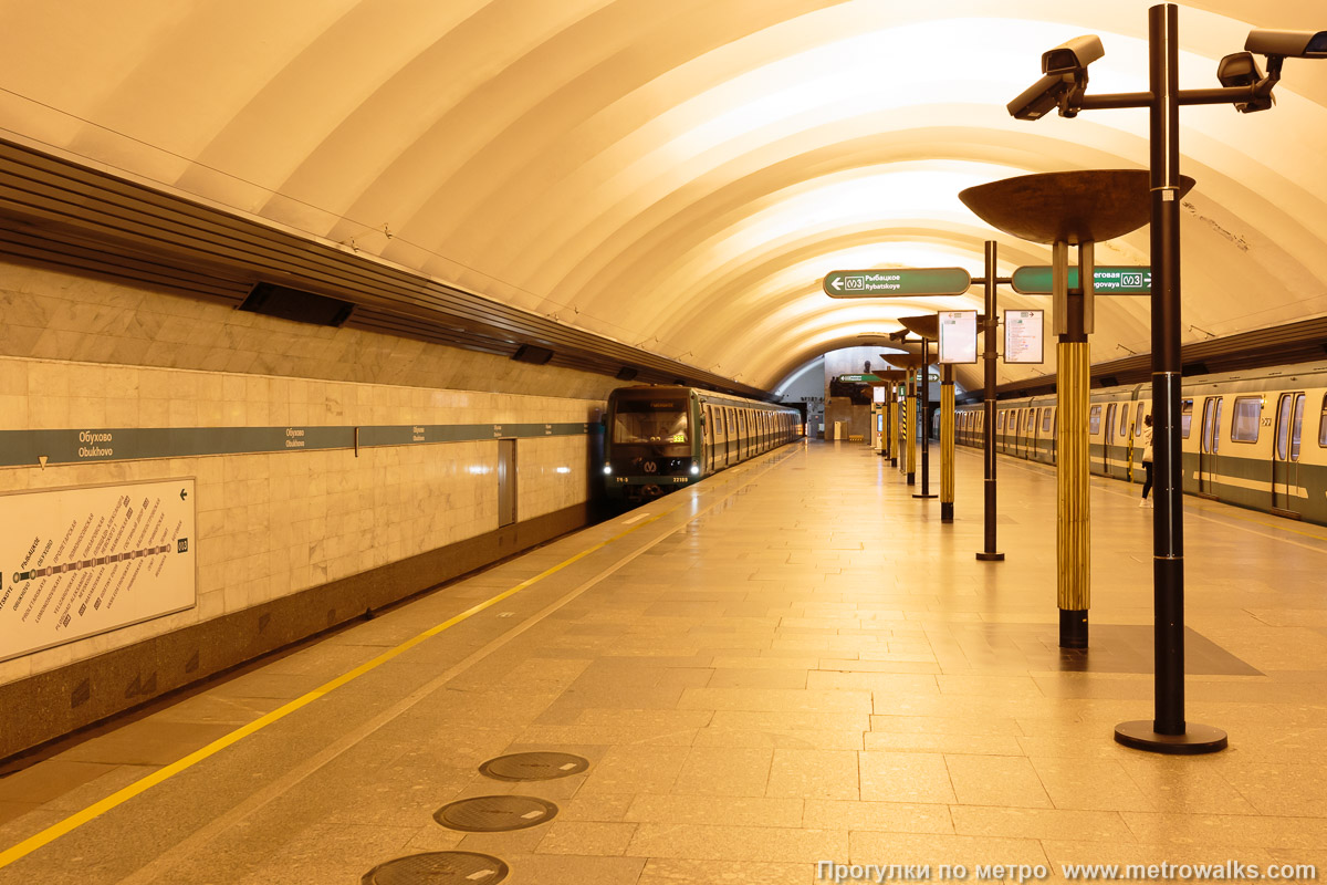 Фотография станции Обухово (Невско-Василеостровская линия, Санкт-Петербург). Край платформы, общий вид. Для оживления пустынной станции — с двумя зелёными поездами модели «Юбилейный».