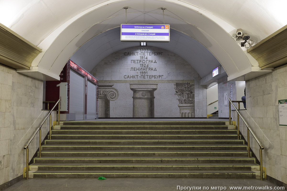 Фотография станции Сенная площадь (Московско-Петроградская линия, Санкт-Петербург). Около перехода. В южном торце центрального зала — переход на станцию Спасскую Правобережной линии. Мозаичное панно «Три века Санкт-Петербурга» (художники — С. Н. Репин, В. В. Сухов, И. Г. Уралов, Н. П. Фомин).