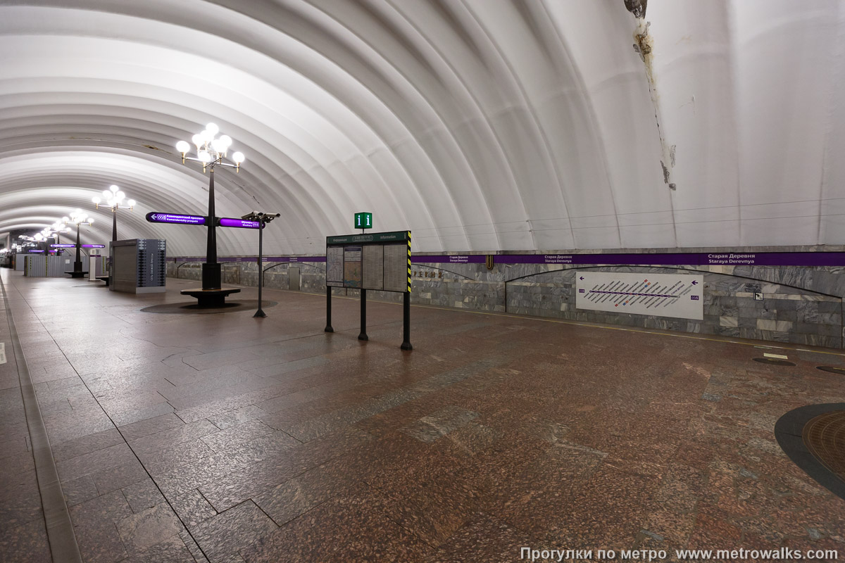 Фотография станции Старая Деревня (Фрунзенско-Приморская линия, Санкт-Петербург). Вид по диагонали. Современный облик: при полном освещении, но с чрезмерным нагромождением лишних объектов на платформе.