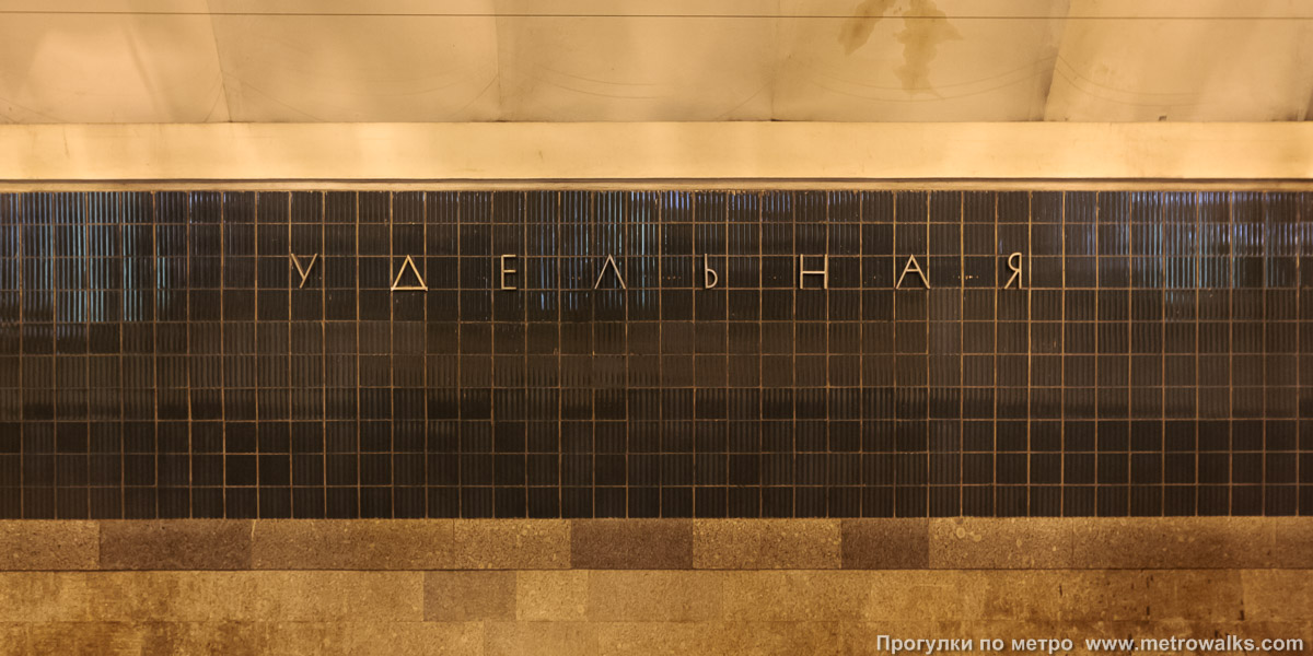 Фотография станции Удельная (Московско-Петроградская линия, Санкт-Петербург). Название станции на путевой стене крупным планом. До наших дней эти металлические буквы не сохранились.
