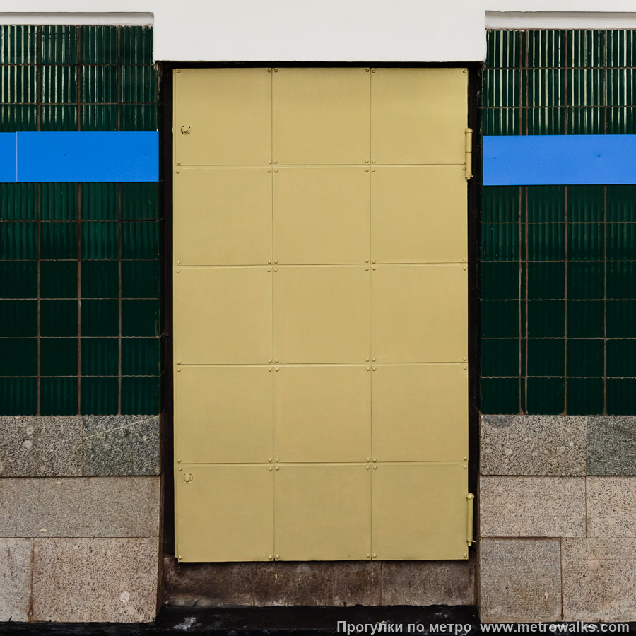 Фотография станции Удельная (Московско-Петроградская линия, Санкт-Петербург). Декоративная технологическая дверь в стене. Раньше они были из нержавеющей стали, но при ремонте 2025 года их просто окрасили жёлтой краской.