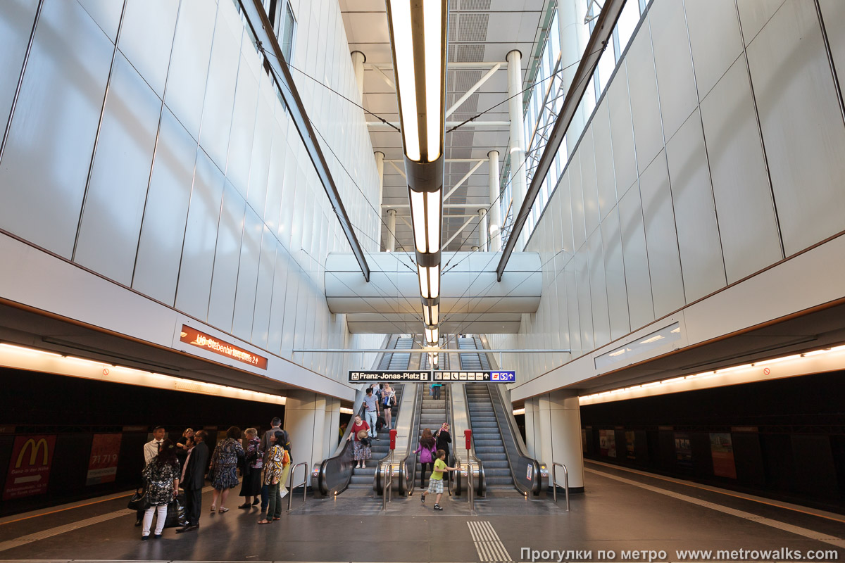 Фотография станции Floridsdorf [Флоридсдорф] (U6, Вена). Выход в город, эскалаторы начинаются прямо с уровня платформы. Часть перекрытия центрального зала отсутствует, станция освещается уличным светом.