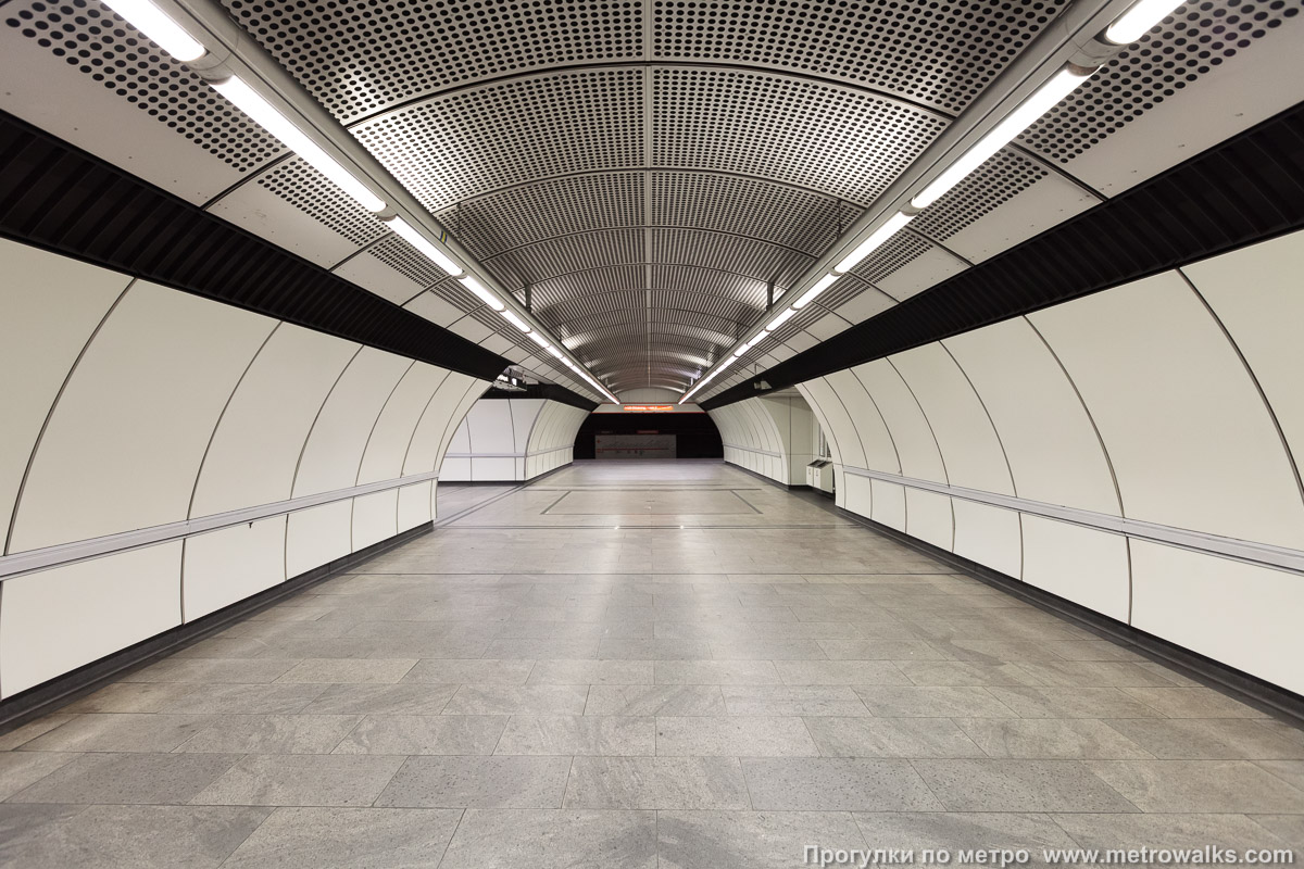 Фотография станции Zippererstraße [Ципперерштрассе] (U3, Вена). Сквозной вид с края платформы через два прохода между пилонами. С одной стороны станции боковые залы соединяются через аванзал в форме прямого тоннеля.