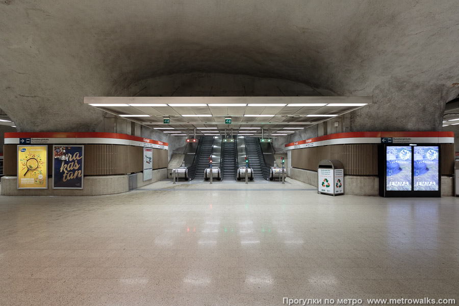 Станция Kamppi / Kampen [Ка́мппи] (Хельсинки). Выход в город, эскалаторы начинаются прямо с уровня платформы. Западный выход — основной, к перекрёстку Runeberginkatu и Salomonkatu.