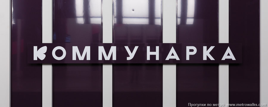 Станция Коммунарка (Троицкая линия, Москва). Название станции на путевой стене крупным планом. Буква «К» украшена крыльями бабочки для усиления весёленького интерьера станции.