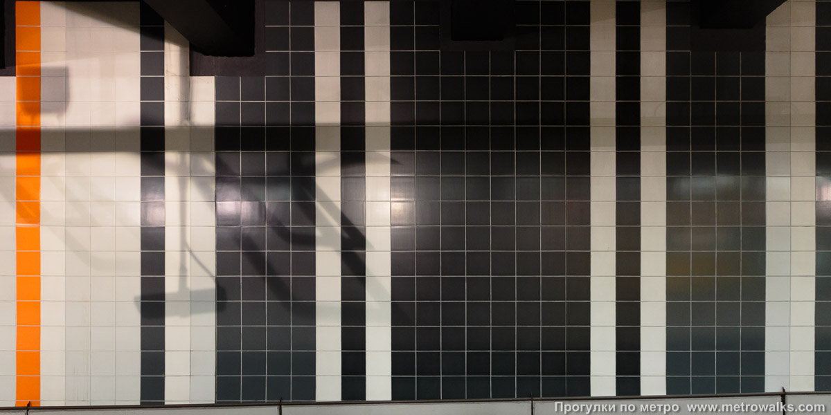 Фотография станции Roi Baudouin / Koning Boudewijn [Руа́ Бодуэ́н / Конинг Баудэвейн] (линия 2 / 6, Брюссель). Декоративное оформление путевой стены крупным планом. Путевая стена отделана квадратной керамической плиткой с полосами всех цветов радуги.