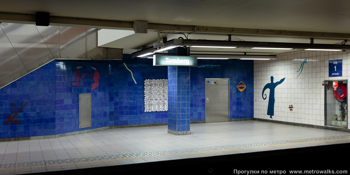 Фотография станции Tomberg [То́мберх] (линия 1, Брюссель). Станционная стена. Станционные стены, облицованные керамической плиткой, украшены силуэтами, напоминающими разнообразных морских гадов.