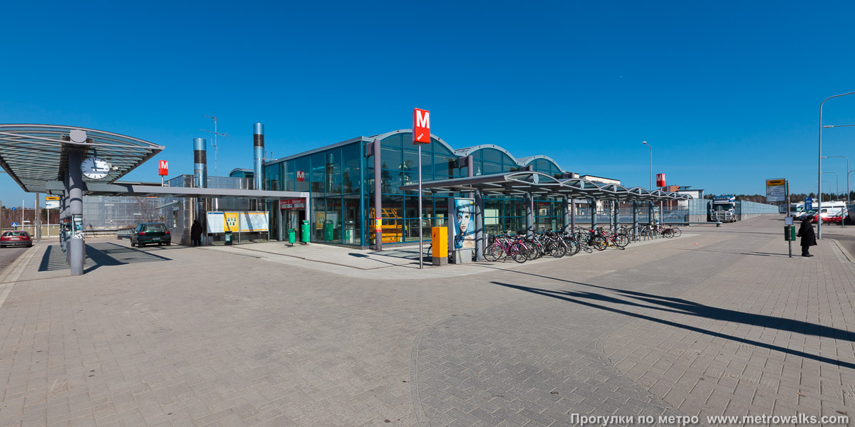 Фотография станции Rastila / Rastböle [Ра́стила] (Хельсинки). Наземный вестибюль станции. Рядом с западным наземным вестибюлем (Karavaanisilta) находится крупная автобусная остановка.