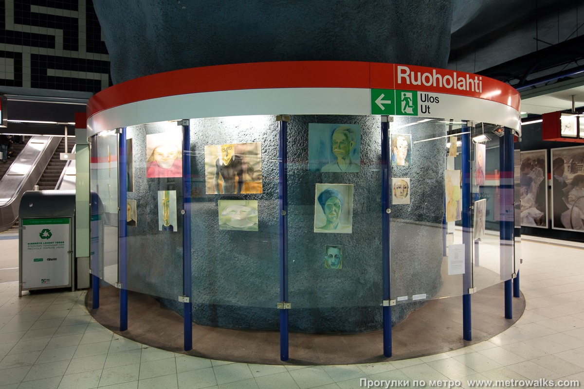 Фотография станции Ruoholahti / Gräsviken [Руо́хола́хти] (Хельсинки). Витрина с художественной инсталляцией на платформе станции. Художественная экспозиция периодически сменяется. Например, в 2009 году здесь была выставка потретов.