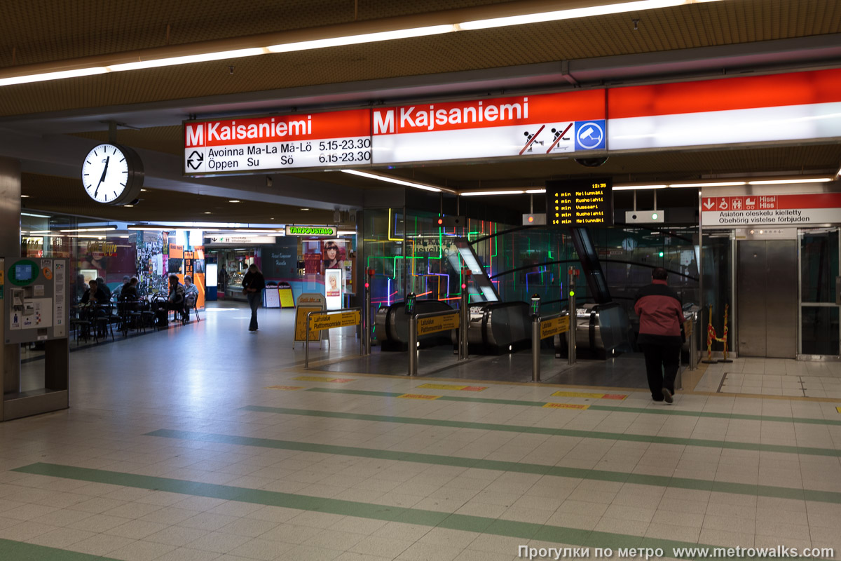 Фотография станции Helsingin yliopisto / Helsingfors universitet [Хе́льсиньин у́лио́писто] (Хельсинки). Эскалаторы в вестибюле. Историческое фото вестибюля (2009) со старым названием станции.