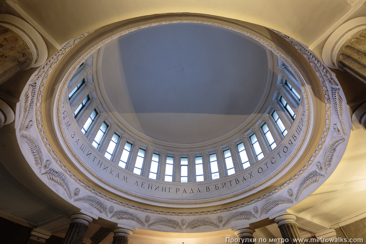 Фотография станции Автово (Кировско-Выборгская линия, Санкт-Петербург). Потолок вестибюля. Чтобы полностью прочитать на куполе прославление «…ЫМ ЗАЩИТНИКАМ ЛЕНИНГРАДА, В БИТВАХ ОТСТОЯВШ…», нужно найти точки в двух противоположных углах вестибюля.