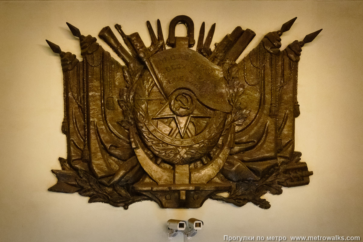 Фотография станции Балтийская (Кировско-Выборгская линия, Санкт-Петербург). Стену над эскалаторами украшает барельеф с изображением ордена Красного Знамени на фоне якоря и многочисленных знамён. Звезда на барельефе ориентирована как на ордене — одним лучом вниз.