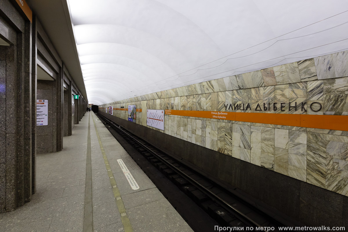 Фотография станции Улица Дыбенко (Правобережная линия, Санкт-Петербург). Боковой зал станции и посадочная платформа, общий вид. Новая фотография, с оранжевой полосой.