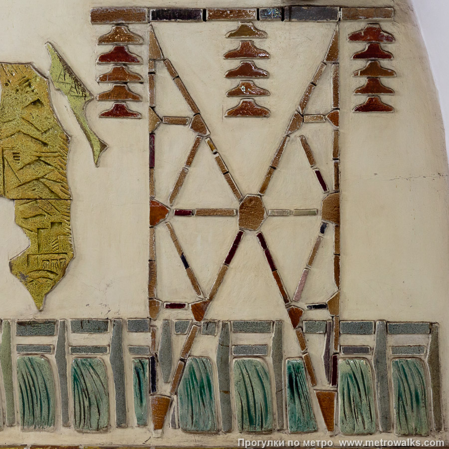 Фотография станции Электросила (Московско-Петроградская линия, Санкт-Петербург). Фрагмент декоративного оформления глухого торца крупным планом. Опора линии электропередачи на фоне гидроэлектростанции.