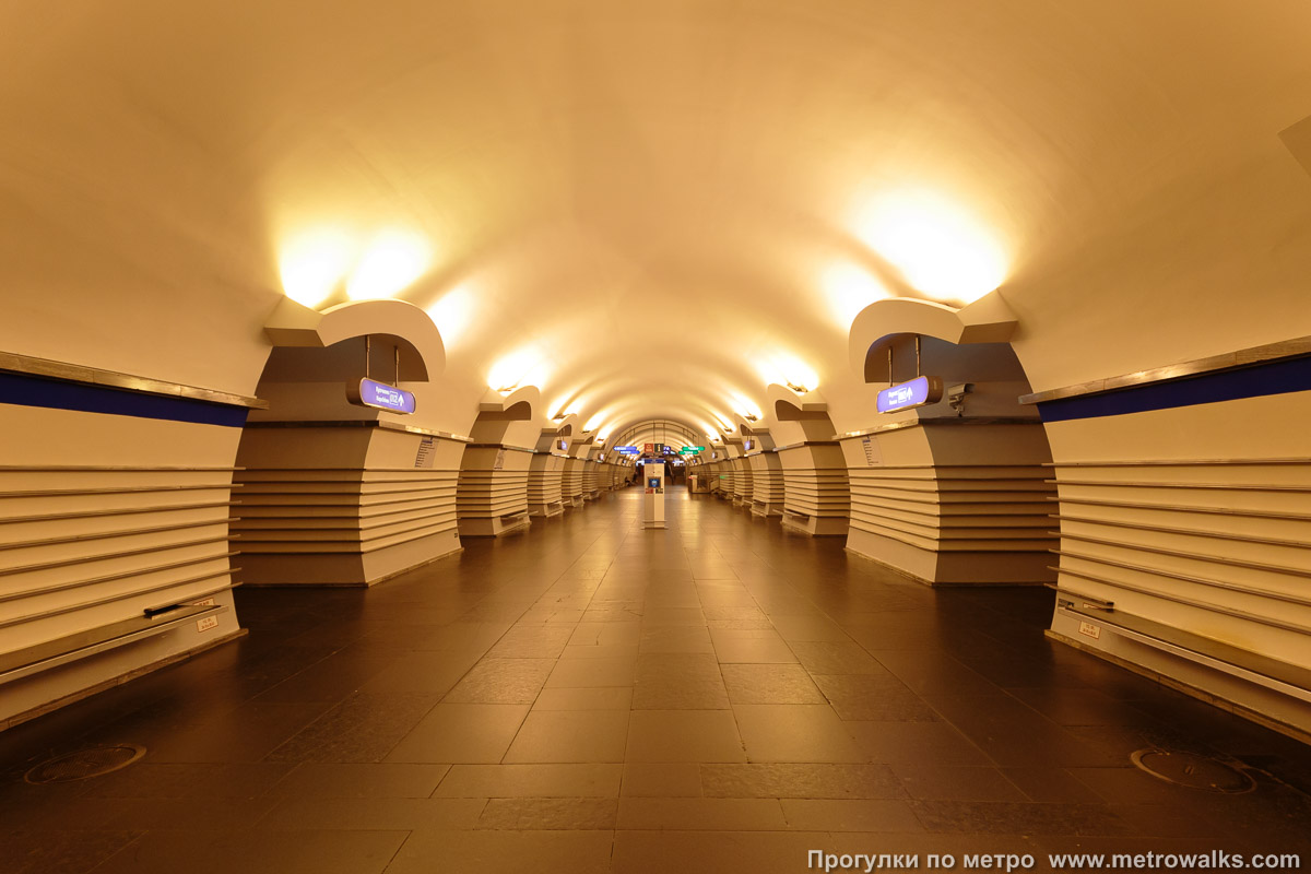 Фотография станции Невский проспект (Московско-Петроградская линия, Санкт-Петербург). Продольный вид центрального зала. С 2003 до 2020 года станция освещалась оранжевыми натриевыми лампами.