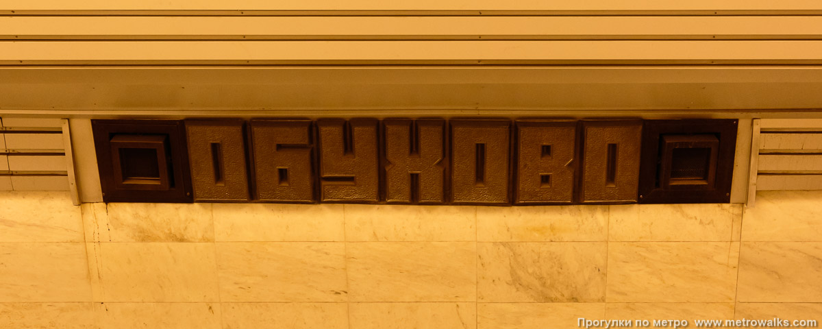 Фотография станции Обухово (Невско-Василеостровская линия, Санкт-Петербург). Название станции на путевой стене крупным планом.