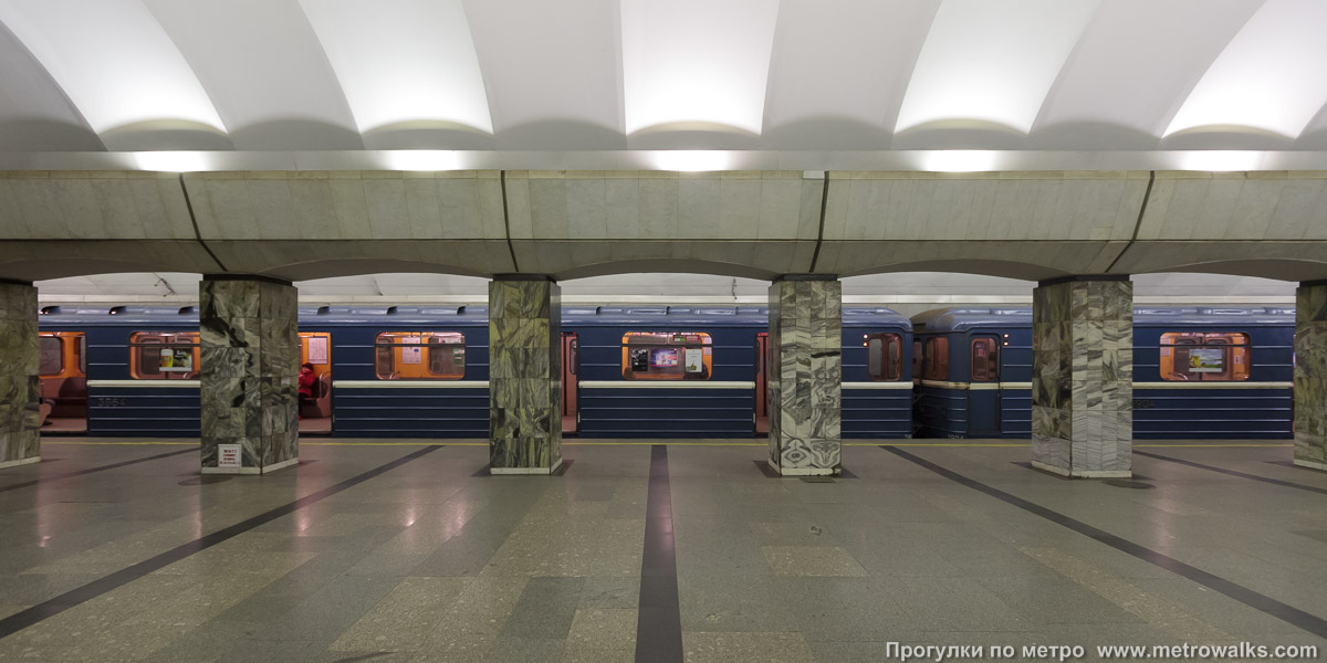 Фотография станции Приморская (Невско-Василеостровская линия, Санкт-Петербург). Поперечный вид, проходы между колоннами из центрального зала на платформу. Для разнообразия — с поездом.