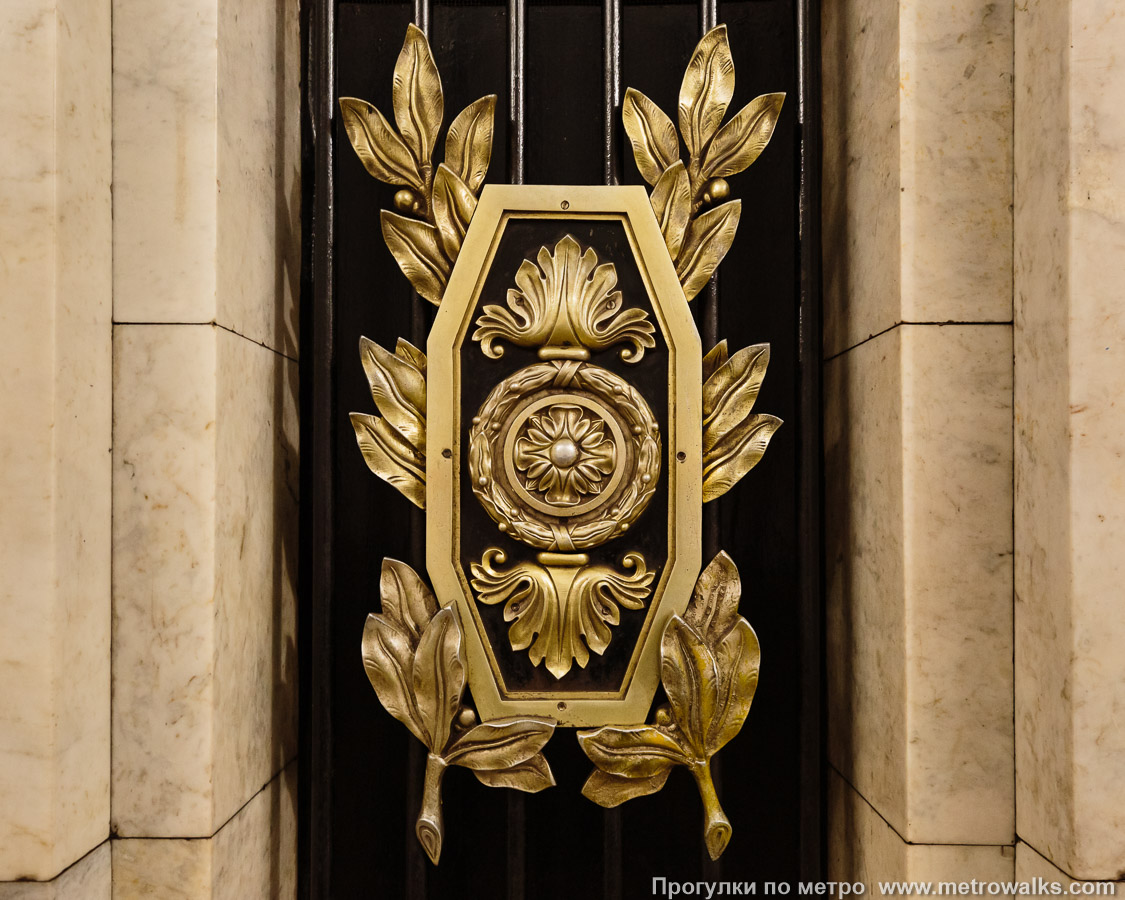 Фотография станции Пушкинская (Кировско-Выборгская линия, Санкт-Петербург). Деталь декоративного оформления пилона: бронзовый щиток.