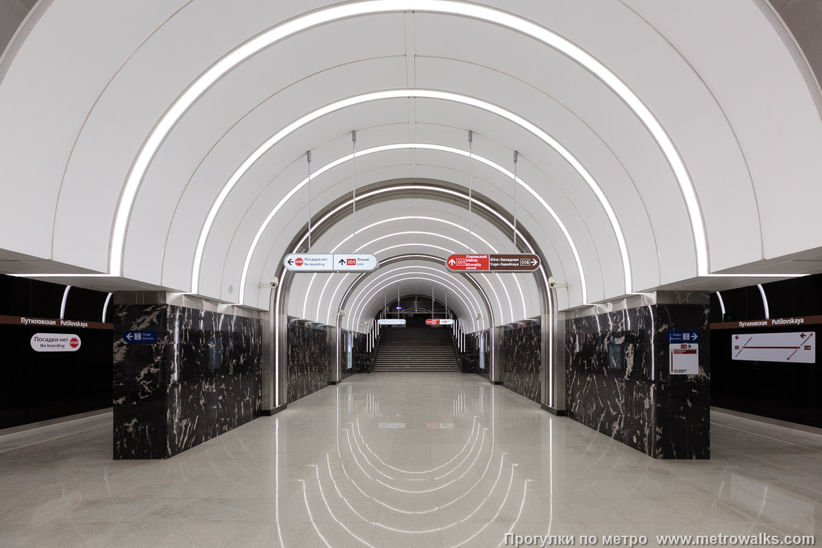 Фотография станции Путиловская (Красносельско-Калининская линия, Санкт-Петербург). В южном торце станции — переход на 1-ю линию. Видно, что проектировщики просчитались с освещением: в переходе намного темнее, чем на станции.