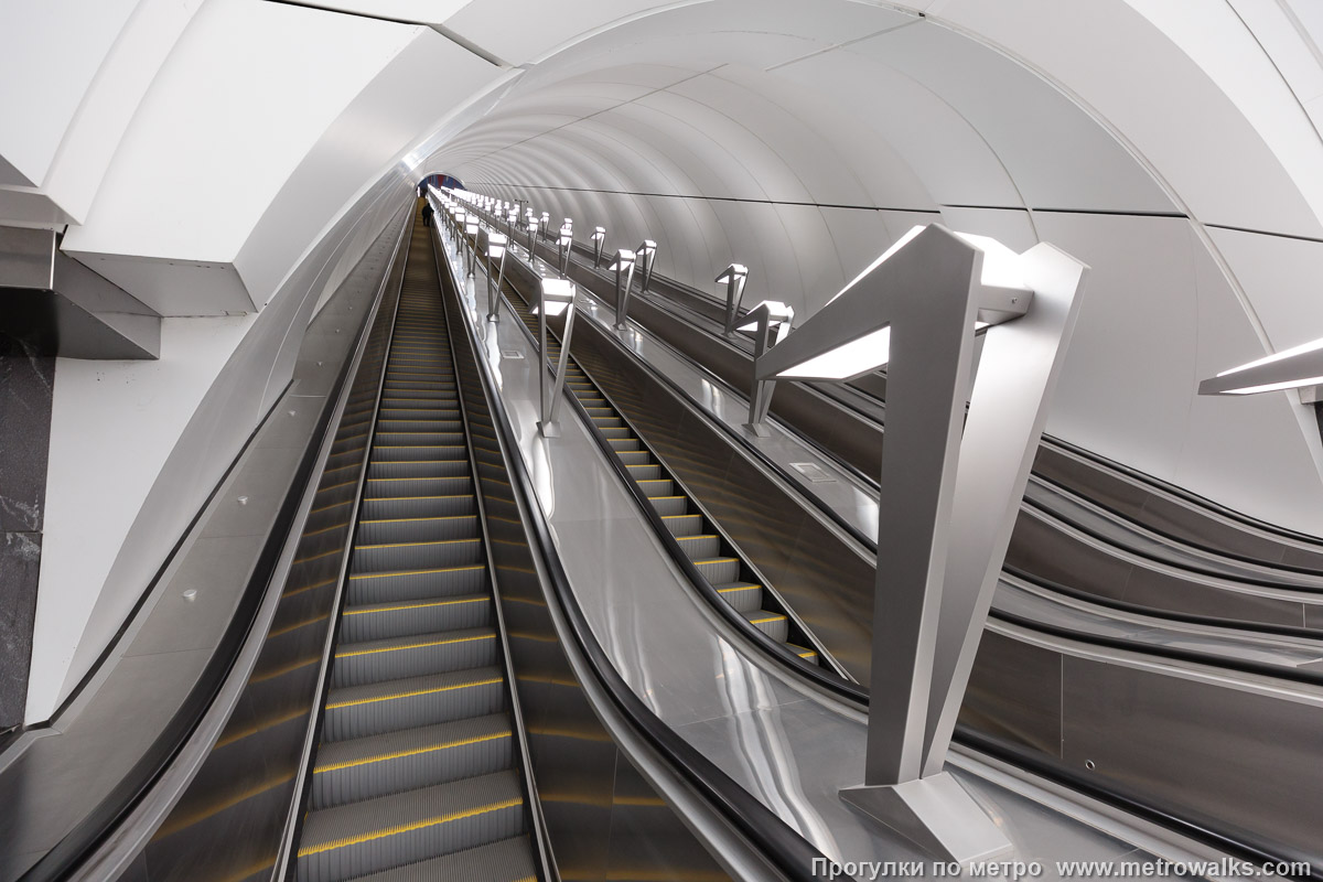 Фотография станции Путиловская (Красносельско-Калининская линия, Санкт-Петербург). Эскалаторы. Для освещения используются светильники-“гуси”, традиционные для Москвы.