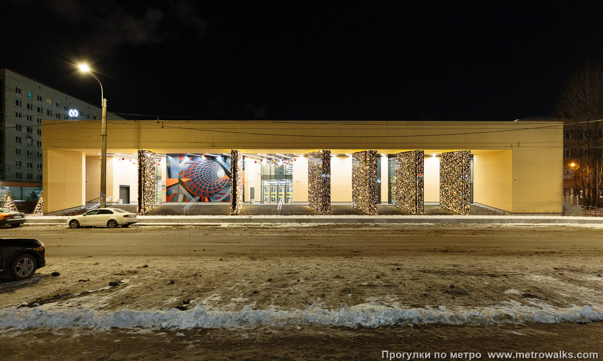 Фотография станции Путиловская (Красносельско-Калининская линия, Санкт-Петербург). Наземный вестибюль станции. Ночной вид, когда парковка вдоль краёв проезжей части не забита машинами. Непонятно, почему сюда к метро не перенесли автобусную остановку.
