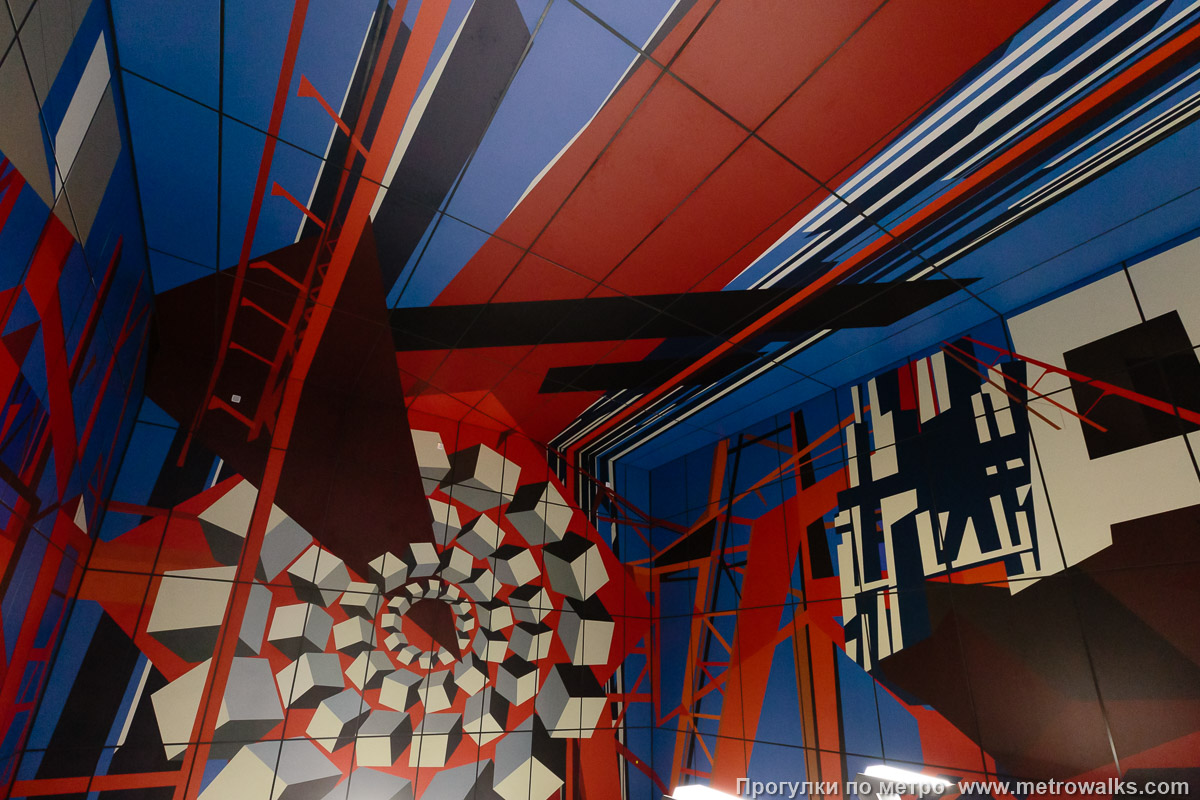 Фотография станции Путиловская (Красносельско-Калининская линия, Санкт-Петербург). Декоративное оформление стены над спуском. Правая сторона. Боковой вид вместо прямого, потому что прямой перекрыт неудачно расположенными светильниками.