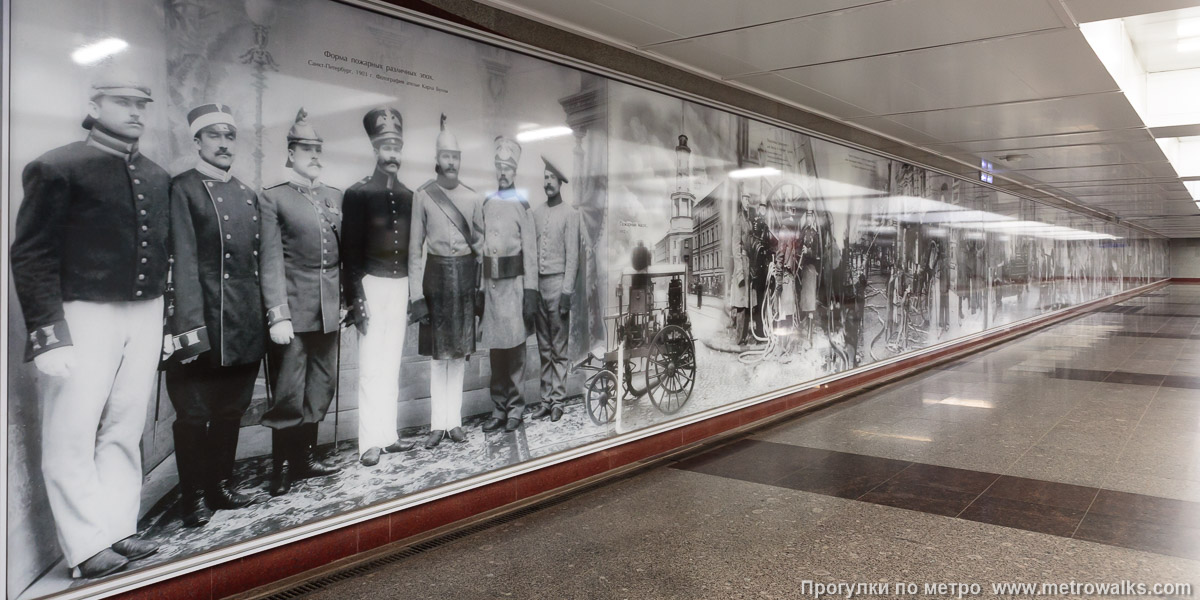 Фотография станции Проспект Славы (Фрунзенско-Приморская линия, Санкт-Петербург). Элементы декоративного оформления подземного перехода. Стена подземного перехода украшена историческими и современными фотоснимками героев-пожарных.