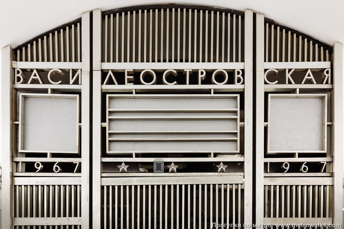 Фотография станции Василеостровская (Невско-Василеостровская линия, Санкт-Петербург). Декоративное оформление глухого торца. Название станции «Василеостровская», три звезды и год открытия. В пустых квадратах раньше располагались часы.