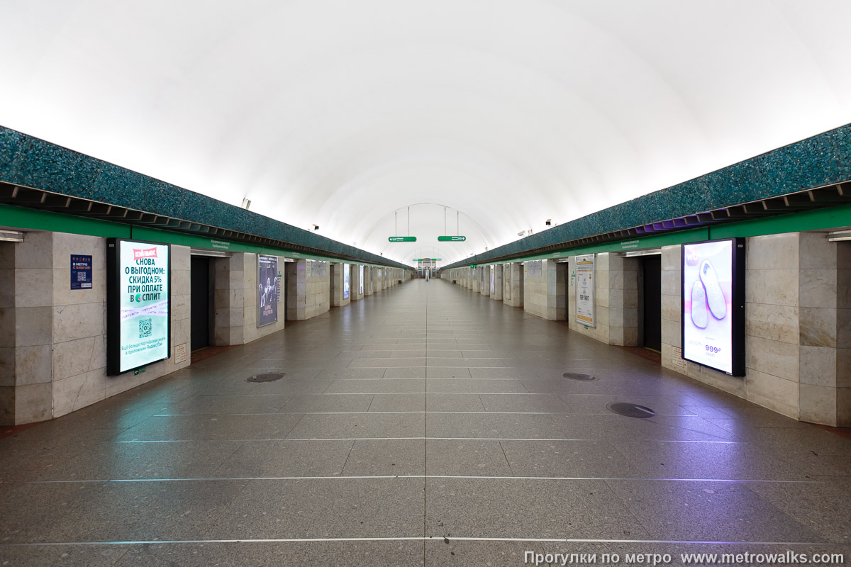 Фотография станции Василеостровская (Невско-Василеостровская линия, Санкт-Петербург). Общий вид по оси станции от входа в сторону глухого торца. С этой стороны станция обильно увешана рекламой.